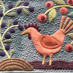 May include: A textile wall hanging featuring a peach-coloured chicken standing on brown soil. The background is a textured grey fabric with swirling patterns. A branch with purple berries and a branch with red berries frame the chicken.