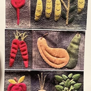 Può includere: Un'opera d'arte tessile con verdure ricamate. Il design include un ravanello rosso, baccelli di piselli gialli, carote rosse, una zucca beige, una mela rossa, una cipolla e piante a foglie verdi. Ogni verdura è su uno sfondo grigio scuro.