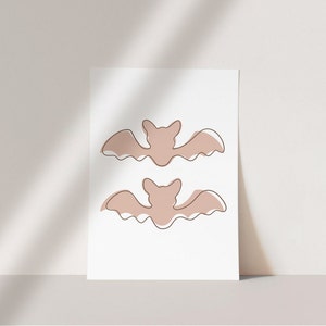 Three Halloween prints. The first print features two blush colored bats, the second print is a blush colored jack’o-lantern and the third print is two adorable blush colored ghosts.