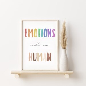 K&ouml;nnte beinhalten: Ein gerahmter Druck mit dem Text "EMOTIONS make us HUMAN" in einem Regenbogen-Farbschema. Der Text ist in einem verspielten, handgezeichneten Stil.