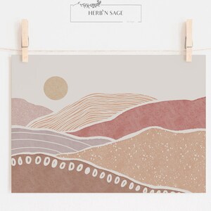 Peut inclure: Impression d'art abstrait repr&eacute;sentant un paysage minimaliste avec des collines roses, brunes et beiges et un soleil jaune. L'impression a un fond textur&eacute; et des points blancs le long du bas.