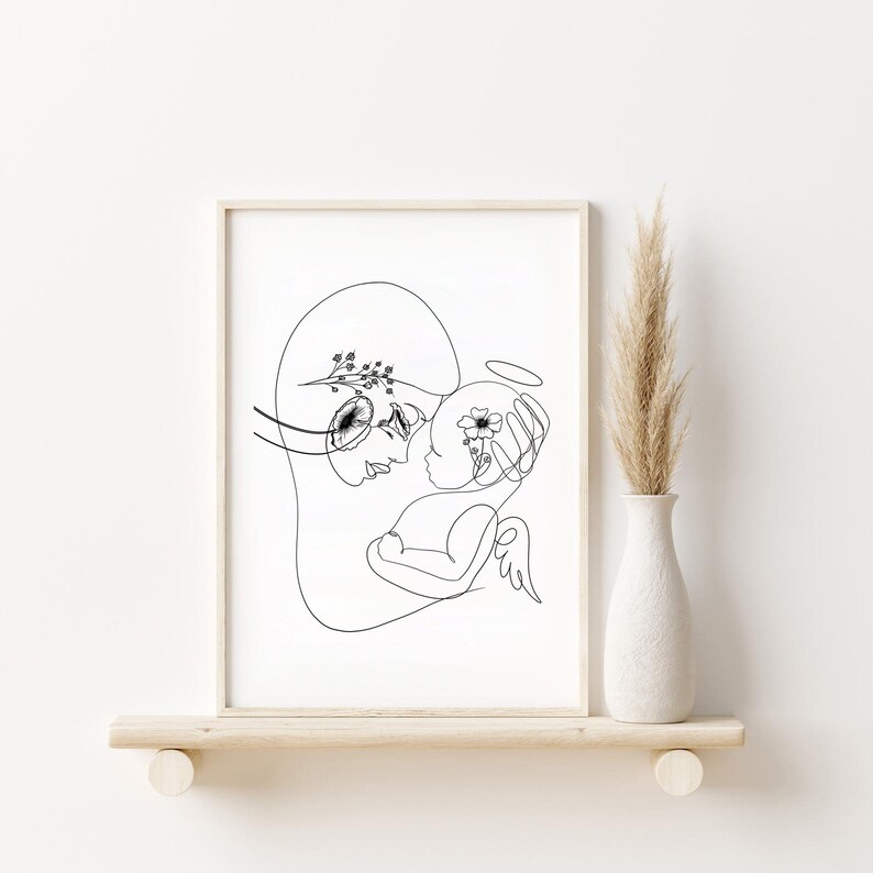 May include: Black and white line art print of a mother and child. The mother is holding the child, who has a halo above their head. Both figures have flowers in their hair.