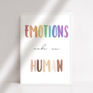 K&ouml;nnte beinhalten: Ein wei&szlig;er gerahmter Druck mit dem Text "EMOTIONS make us HUMAN" in Regenbogen- und braunen Aquarellbuchstaben.