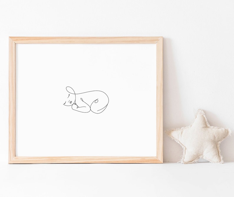 Puede incluir: Un dibujo lineal simple de un beb&eacute; durmiendo en un marco de madera. El dibujo es en blanco y negro y est&aacute; sobre un fondo blanco. Una almohada en forma de estrella beige est&aacute; en primer plano.