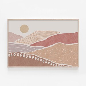 Peut inclure: Une impression d'art num&eacute;rique repr&eacute;sentant un paysage minimaliste avec un soleil, des collines et une palette de couleurs brun, beige et rose. L'impression est encadr&eacute;e dans un cadre en bois clair.