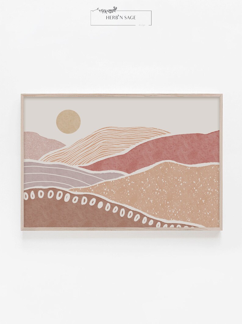 Peut inclure: Une impression d'art num&eacute;rique repr&eacute;sentant un paysage minimaliste avec un soleil, des collines et une palette de couleurs brun, beige et rose. L'impression est encadr&eacute;e dans un cadre en bois clair.