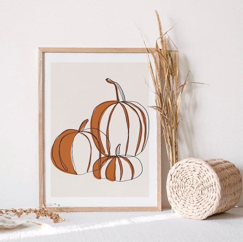 A seasonal fall print. This fall print has three pumpkins draw with a continuous black line. Random parts of the three pumpkins are painted orange and the background is a beige with a white border.