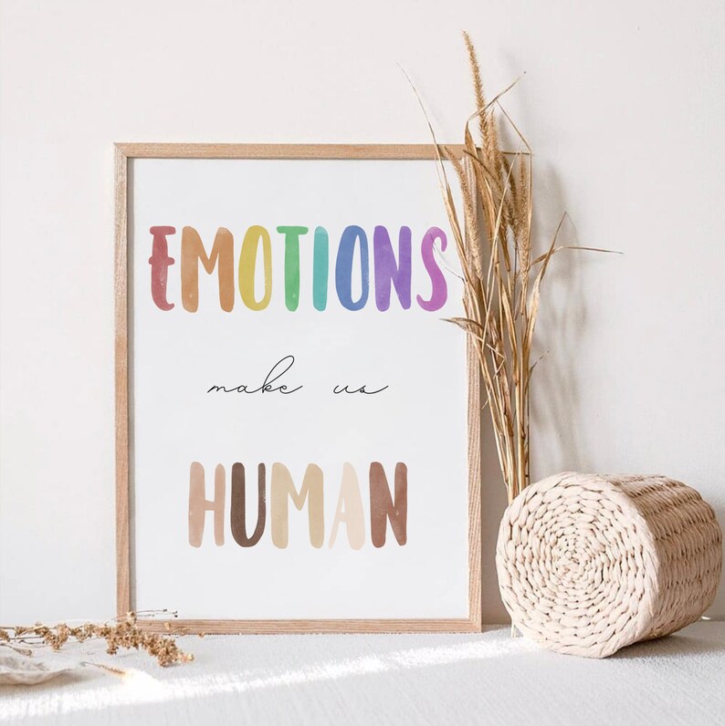 K&ouml;nnte beinhalten: Ein gerahmter Druck mit dem Text "EMOTIONS make us HUMAN" in Regenbogen- und braunen Aquarellbuchstaben. Der Druck ist auf wei&szlig;em Hintergrund und hat einen hellen Holzrahmen.