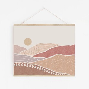 Peut inclure: Impression d'art abstrait repr&eacute;sentant un paysage minimaliste avec des collines roses, brunes et beiges et un soleil jaune. L'impression est encadr&eacute;e d'un cadre en bois clair.