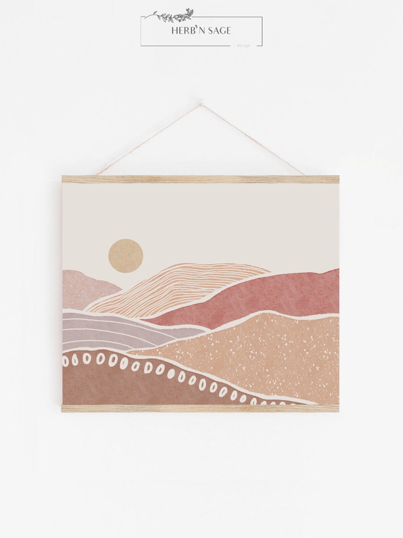 Peut inclure: Impression d'art abstrait repr&eacute;sentant un paysage minimaliste avec des collines roses, brunes et beiges et un soleil jaune. L'impression est encadr&eacute;e d'un cadre en bois clair.