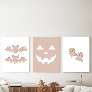 Three Halloween prints. The first print features two blush colored bats, the second print is a blush colored jack’o-lantern and the third print is two adorable blush colored ghosts.