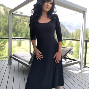 Vestido negro de largo medio con mangas 3/4.