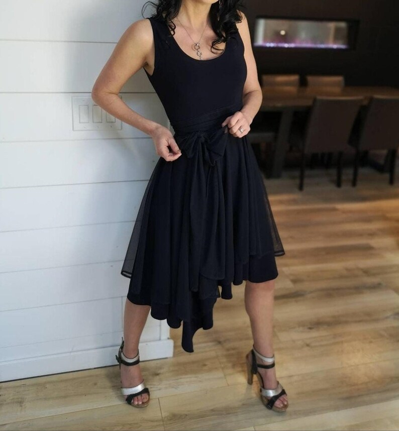 Short flowy dress. This navy dress is classic and fun with a double layer circle skirt and unsymmetrical hemline. Jackets sold separately.
