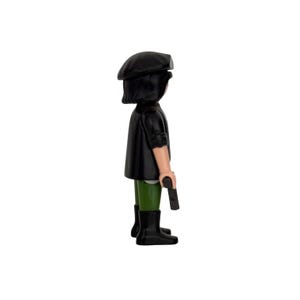 May include: A black and green figurine of a person wearing a black beret and holding a black gun. The figurine is standing on a white background.
