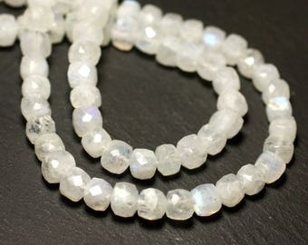 May include: A strand of white moonstone beads with a faceted, square shape. The beads are strung on a clear thread and have a subtle iridescent sheen.