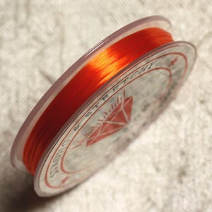 May include: A spool of bright orange elastic cord, labeled "Stretch Magic" with a diamond logo.