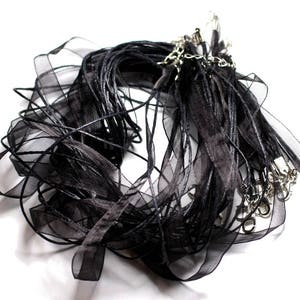 May include: A bundle of black ribbon and cord with silver clasps. The ribbon is sheer and the cord is a thicker, matte black.