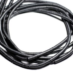 Op de afbeelding: Een streng grijze metalen kralen, elke kraal is een spoel van metaal, de kralen zijn in een cirkel gerangschikt.