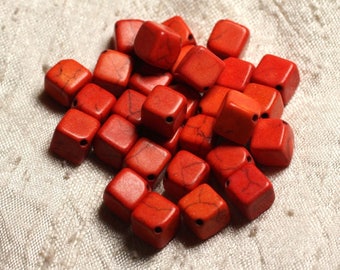 May include: A collection of vibrant red square beads with rounded edges. Each bead has a small hole for stringing and natural veining patterns. The beads are scattered on a textured, off-white surface, ideal for jewelry making.