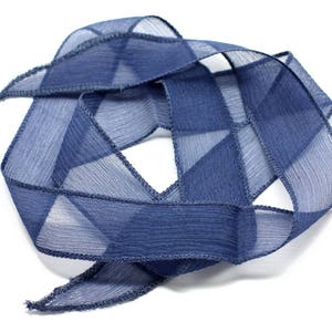 May include: A blue sheer ribbon with a textured finish. The ribbon is folded and twisted into a decorative shape.