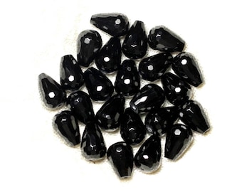 May include: A group of black faceted teardrop-shaped beads. The beads are made of glass or crystal and have a shiny, polished finish.