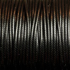 Puede incluir: Primer plano de un cordón encerado negro, mostrando la textura trenzada.