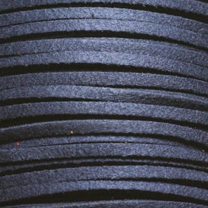 May include: Close-up of a spool of dark blue leather cord. The cord is tightly wound and has a smooth, textured surface.