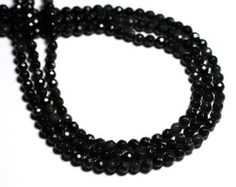 May include: A strand of black gemstone beads, likely obsidian, with a faceted finish. The beads are strung on a clear thread and are arranged in a circular pattern.