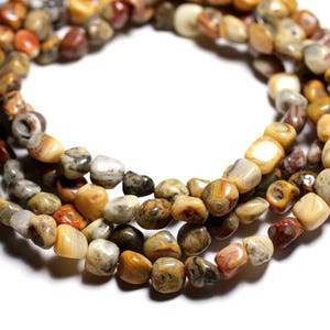 Peut inclure: Un brin de perles de pierre d'agate de couleur marron, blanche et orange. Les perles sont de forme irrégulière et ont une finition naturelle et polie.