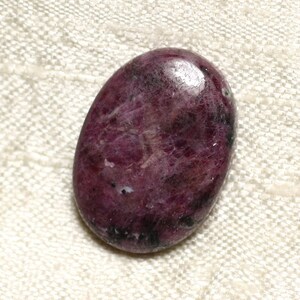 May include: A smooth, oval-shaped, dark purple gemstone with a mottled pattern. The stone has a glossy finish.