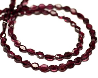 May include: A strand of deep red faceted gemstone beads. The beads are oval shaped and have a smooth, polished finish.