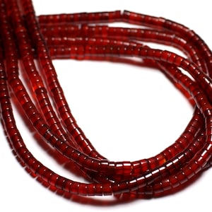 May include: A strand of deep red carnelian beads, each bead is cylindrical and slightly rounded. The beads are strung together to form a long necklace.