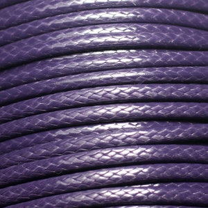 May include: Close-up of a reel of purple braided cord. The cord has a textured, snake-like pattern.