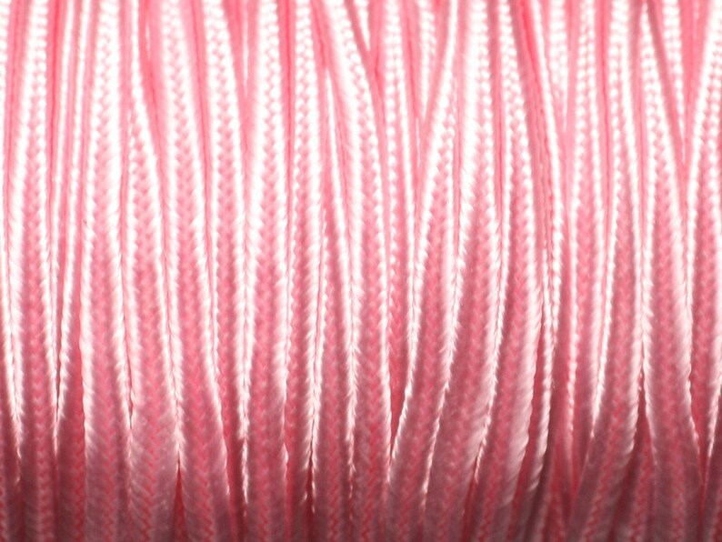 Puede incluir: Primer plano de un carrete de cord&oacute;n rosa. El cord&oacute;n est&aacute; enrollado firmemente, creando una superficie texturizada con l&iacute;neas verticales. El color es un rosa pastel suave, con reflejos y sombras que a&ntilde;aden profundidad a la imagen. El cord&oacute;n parece estar hecho de un material liso, posiblemente sint&eacute;tico.