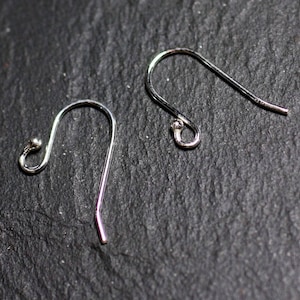 Peut inclure: Deux crochets d'oreille en argent avec une petite boule à l'extrémité de chaque crochet.
