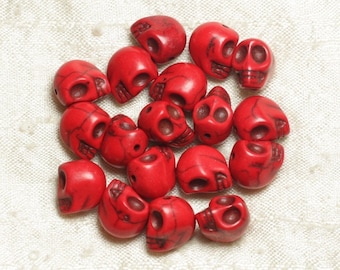 May include: A collection of red skull-shaped beads made of stone. The beads are about 1 inch in diameter and have a smooth, polished finish.