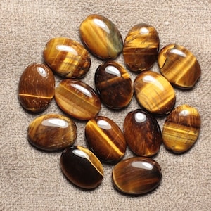 Puede incluir: Una colección de piedras de ojo de tigre de forma ovalada, cada una con un patrón único de rayas marrones y doradas. Las piedras son lisas y pulidas, con un acabado brillante.