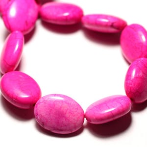 May include: A close-up of a strand of bright pink oval beads. The beads have a smooth, glossy finish with subtle veining. The beads are arranged in a circular shape, suggesting a bracelet or necklace.