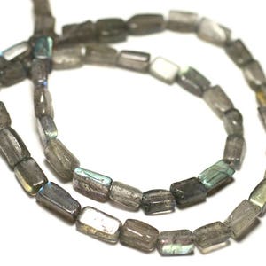 Può includere: Una collana di perline di labradorite grigia e iridescente. Le perline sono rettangolari e hanno una finitura liscia e lucida.