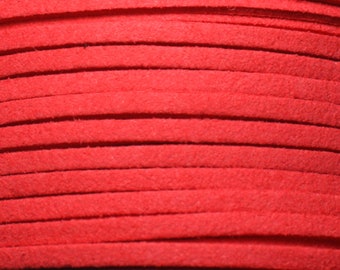May include: Close-up of a spool of red suede cord. The cord is wound tightly and has a soft, velvety texture.