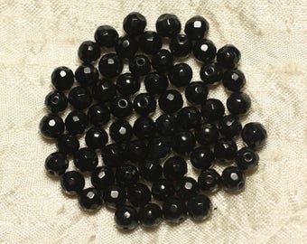 May include: A pile of black faceted glass beads. The beads are small and round, and they have a shiny finish.