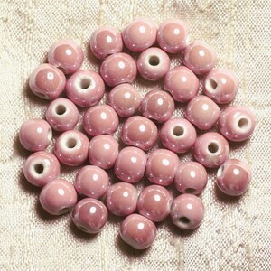 May include: A collection of approximately 25 pink ceramic beads with white holes. The beads are round and have a glossy finish.