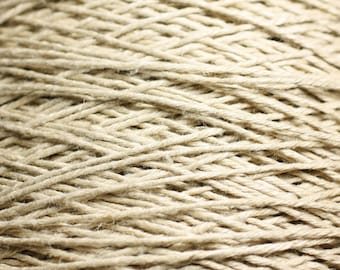 May include: Close-up of a tightly wound ball of natural beige twine. The twine is made of natural fibers and has a rough texture.