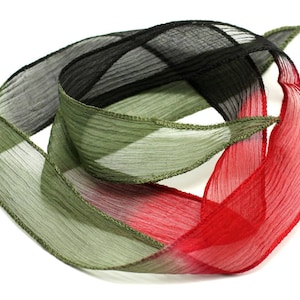 May include: A multi-colored ribbon with shades of black, green, and red. The ribbon is made of a sheer, delicate fabric and is twisted into a spiral shape.
