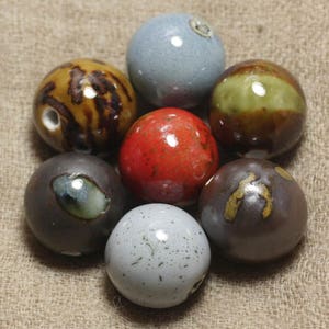 Peut inclure: Une collection de sept sphères en céramique de différentes couleurs et motifs, notamment brun, gris, rouge et vert. Les sphères sont disposées en cercle.