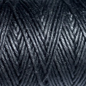 May include: Close-up of black waxed cotton cord, showing the tightly woven texture of the fibres.