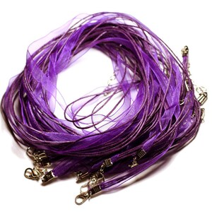 May include: A collection of purple sheer ribbon necklaces with silver clasps. The ribbons are a vibrant shade of purple with a metallic sheen, and are bunched together against a white background. Each necklace has a small clasp.
