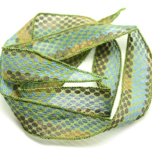 May include: A green, blue, and brown patterned ribbon with a dotted design. The ribbon is folded and twisted into a circle.