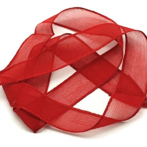 May include: Red sheer ribbon tied in a decorative knot. The ribbon is soft and translucent, with a subtle sheen.