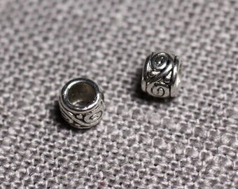 May include: Two silver metal beads with a decorative swirl design. The beads are round and have a hole in the center.